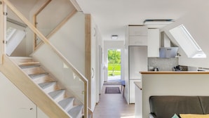 Un interno moderno con una scala, una cucina e un soggiorno.