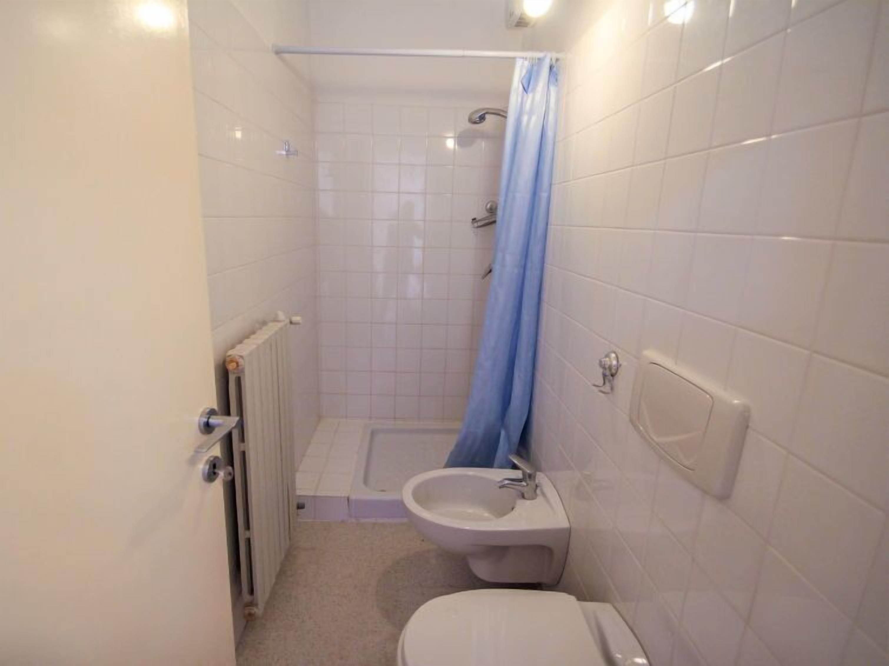 Een kleine badkamer met tegels, een douche, toilet en wastafel.