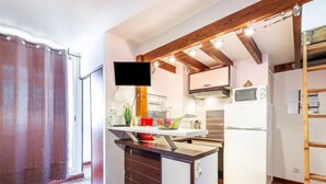 Una cucina compatta con soffitto in legno, forno a incasso e microonde.