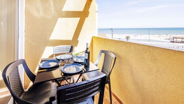 Un balcone con un tavolo apparecchiato per due, vista sulla spiaggia.