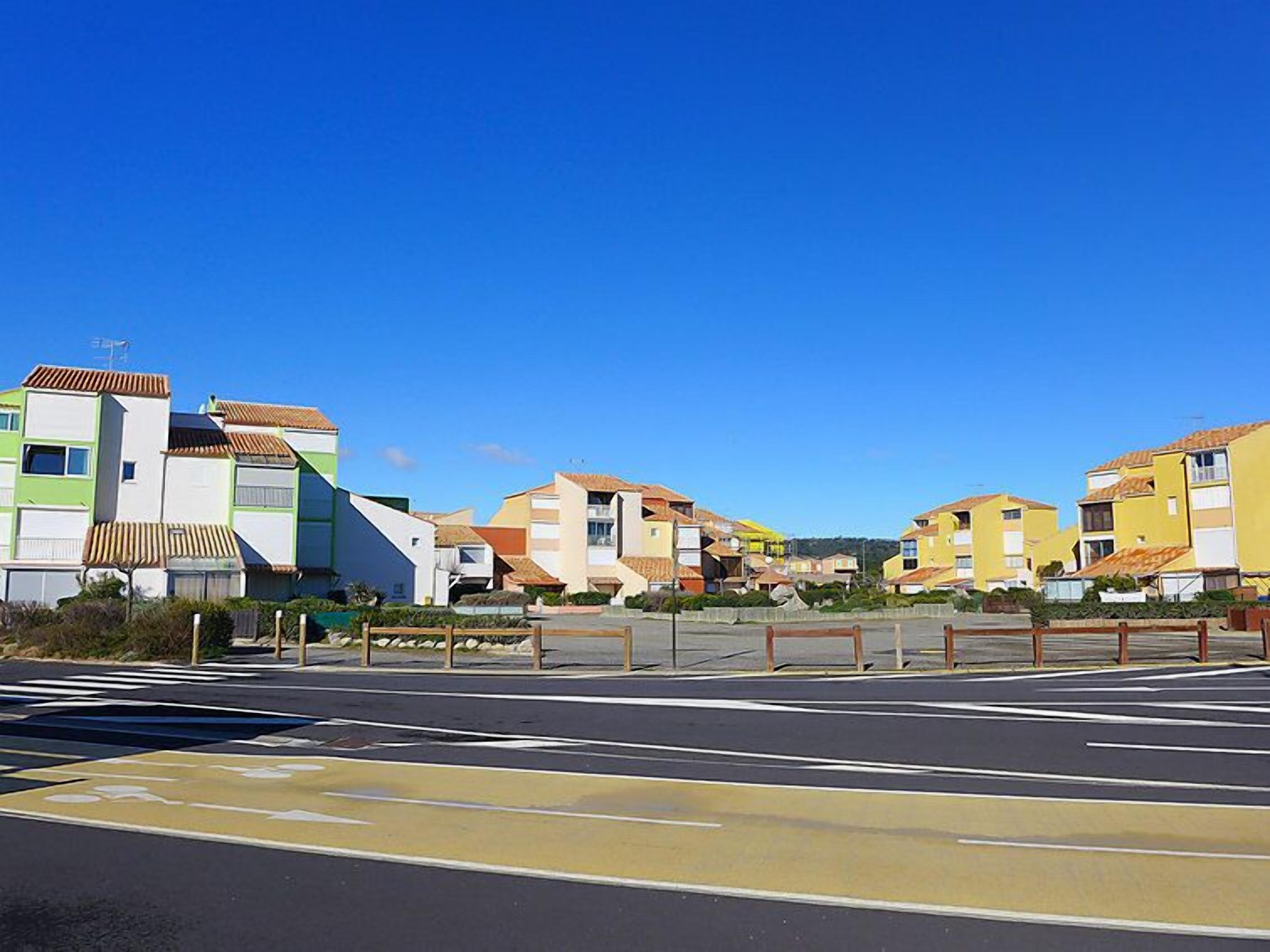 Zona residencial amb cases de colors vives, cel blau clar i pas de vianants.