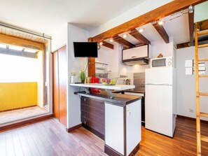 A compact kitchen with a built-in microwave, a small refrigerator, and a wooden ceiling. - Les Balcons de la Méditerranée by Interhome (Narbonne-Plage)