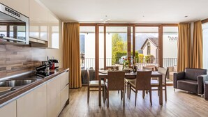 Une cuisine moderne avec un coin repas, un plancher en bois et de grandes fenêtres offrant une vue sur la montagne.