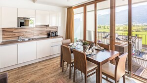 Une cuisine moderne avec des meubles en bois, un four encastré et un coin repas avec une table dressée pour quatre personnes.