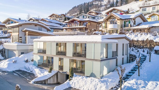 Un hôtel moderne à la façade en verre, situé dans une région montagneuse enneigée.