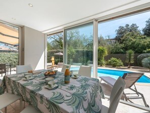 A dining area with a table set for four, overlooking a swimming pool and garden.