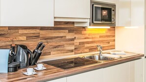 Une cuisine moderne avec un revêtement mural en bois, des appareils électroménagers en acier inoxydable et des meubles blancs.