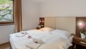Une chambre d’hôtel avec un lit, une table de chevet, une fenêtre avec des rideaux et une vue sur des rochers.