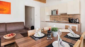 Une cuisine moderne avec des meubles en bois, un four encastré et un plan de travail sur lequel se trouvent une bouilloire et des couteaux.