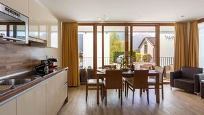Une cuisine moderne dotée d’un four encastré et d’un coin repas avec des chaises et une table en bois.