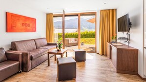 A modern living room with a brown leather sofa, a wooden coffee table, and a flat-screen TV mounted on the wall. - Apartment Emma by Interhome (Kaprun)