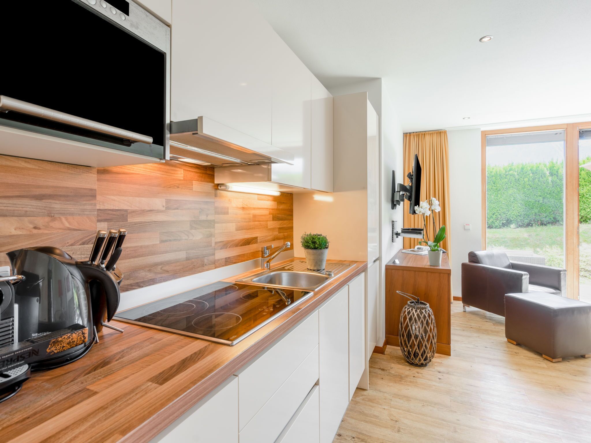 Une cuisine moderne avec des éléments en bois, une cuisinière intégrée et un évier.