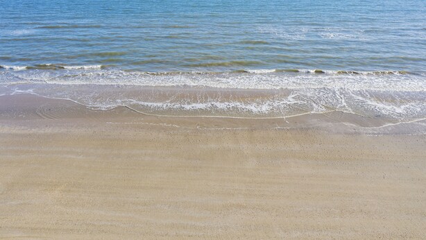 Una playa con arena dorada y olas suaves.