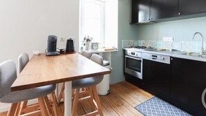A compact kitchen with a wooden table and chairs, a stove, oven, and a dishwasher.