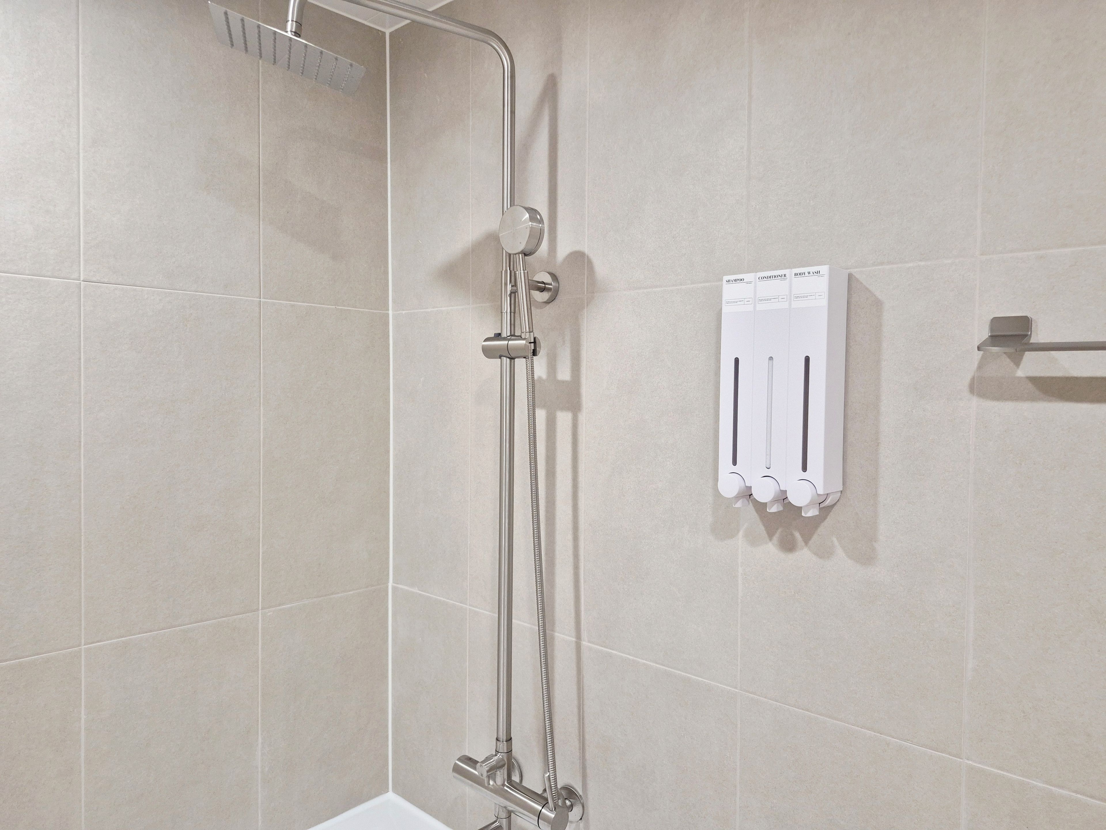 Doccia con soffione a mano e pannello comandi a parete.