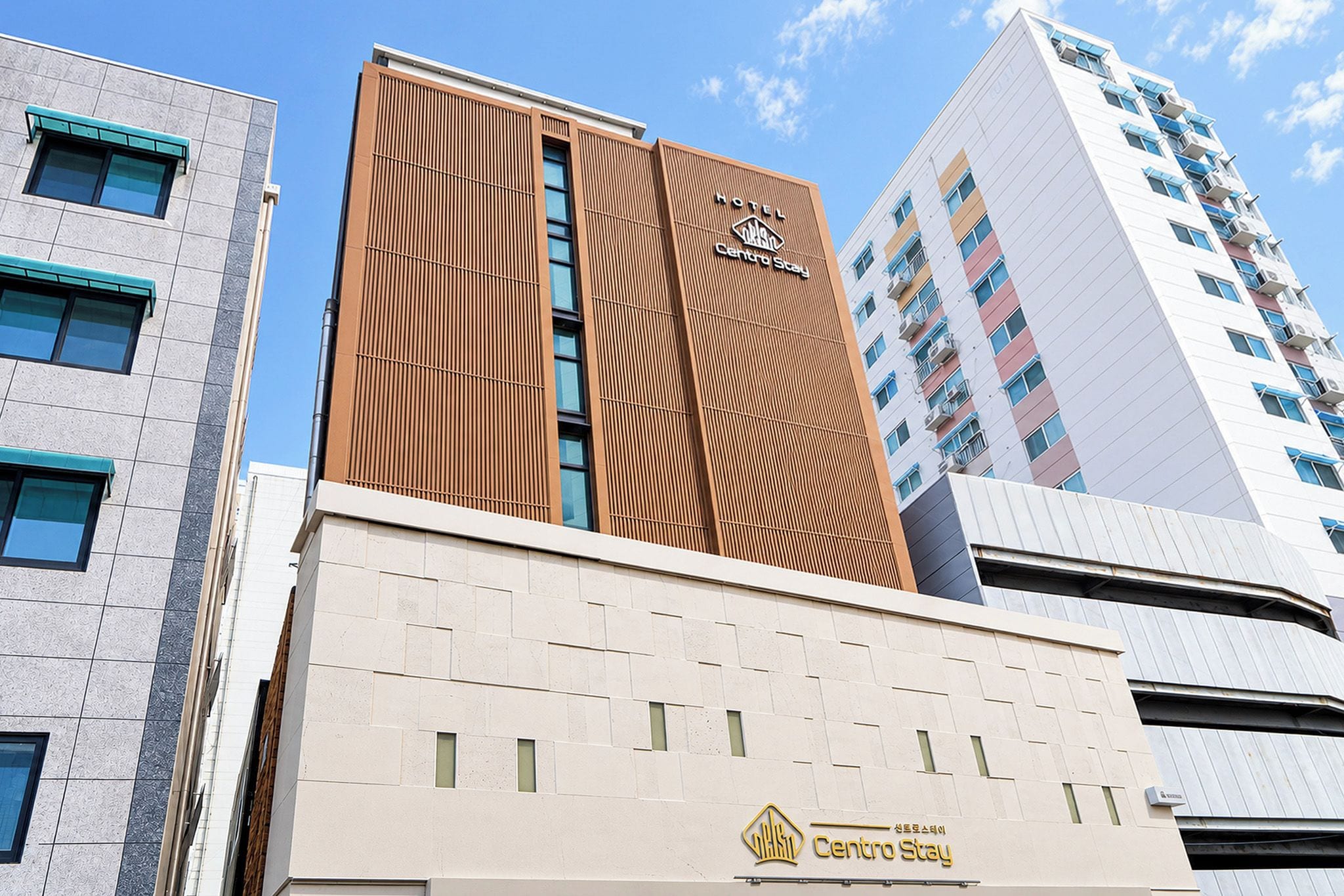 A hotel building with a modern facade, a prominent logo, and a sign indicating 'Centro Stay.'