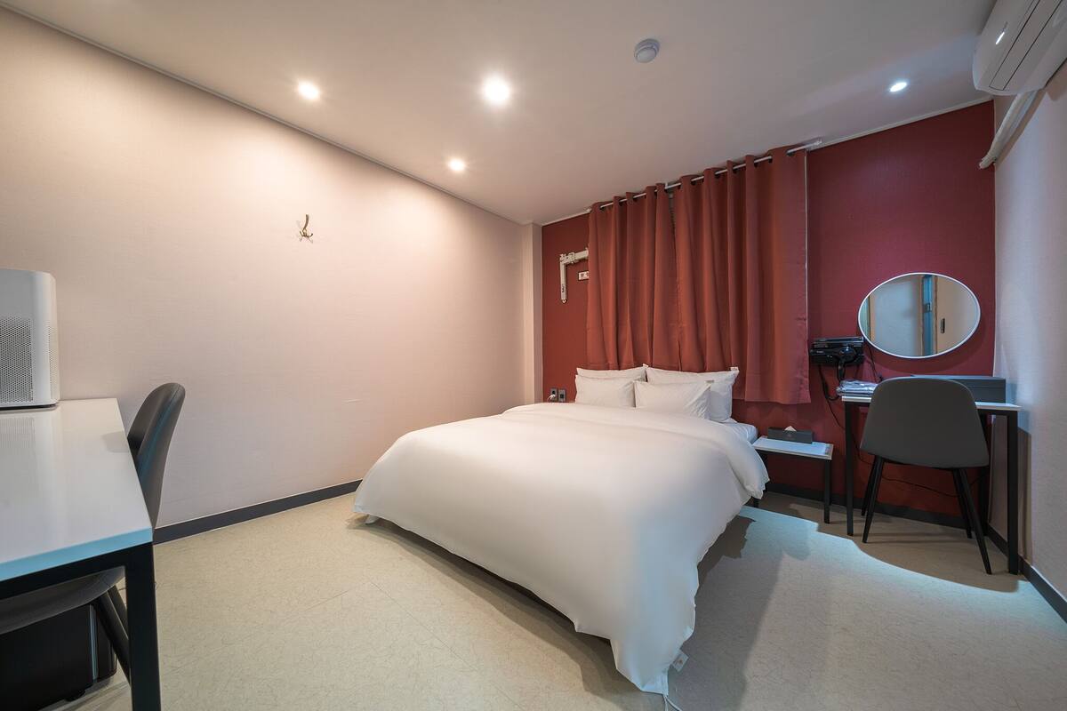 A hotel room with a bed, desk, chair, and a small table.