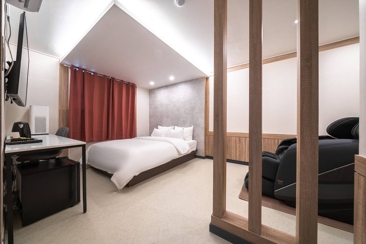 A modern hotel room with a bed, desk, and seating area.