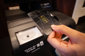 Una mano sosteniendo una tarjeta negra con el texto 'HOTEL KOH ASAKUSA'.