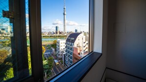 A view from a window overlooking a cityscape with a prominent tower, modern buildings, and a river. - COB HOTEL ASAKUSA (Tokyo)