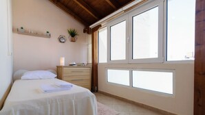Une chambre à coucher comprenant un lit, une commode, une fenêtre et une étagère ornée d’objets décoratifs.