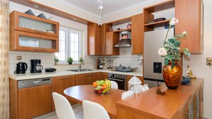 Une cuisine moderne avec des meubles en bois, un îlot central doté de chaises, un panier de fruits et un vase décoratif.