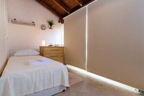 Ein Schlafzimmer mit einem Bett, einer hölzernen Kommode, einem Regal mit Dekoration und einer Zimmerpflanze.