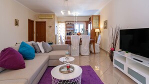 Un salon comprenant un canapé, une table basse, un meuble pour la télévision, ainsi qu’un coin repas avec des chaises et une table.