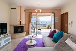A living room with a fireplace, sofa, and a balcony with a view.