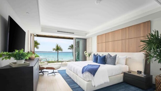 Une chambre moderne avec un grand lit, une télévision et une vue sur l’océan.