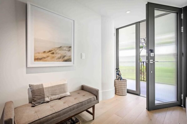A modern living room with a sofa, a large abstract painting, and a sliding glass door leading to a balcony.