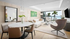 Un salon moderne avec une table à manger ronde, des canapés et une grande fenêtre donnant sur la mer.