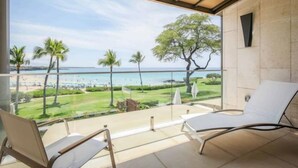 Un balcon avec vue sur la plage et l’océan. On y trouve des chaises longues et une paroi en verre.