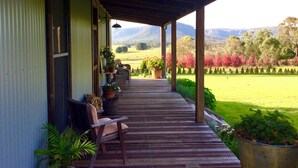Une véranda couverte avec un plancher en bois, des plantes en pot et un banc.
