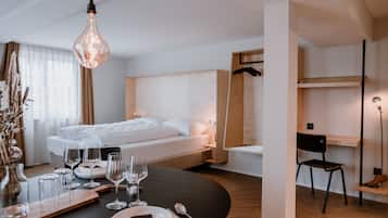 A modern hotel room with a neatly made bed, a dining table set for two, and a chair.