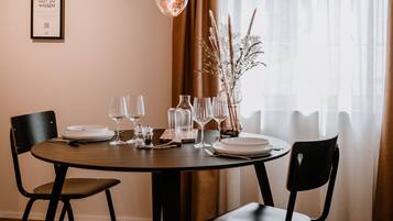 A dining area with a round table, four chairs, and a hanging light fixture.