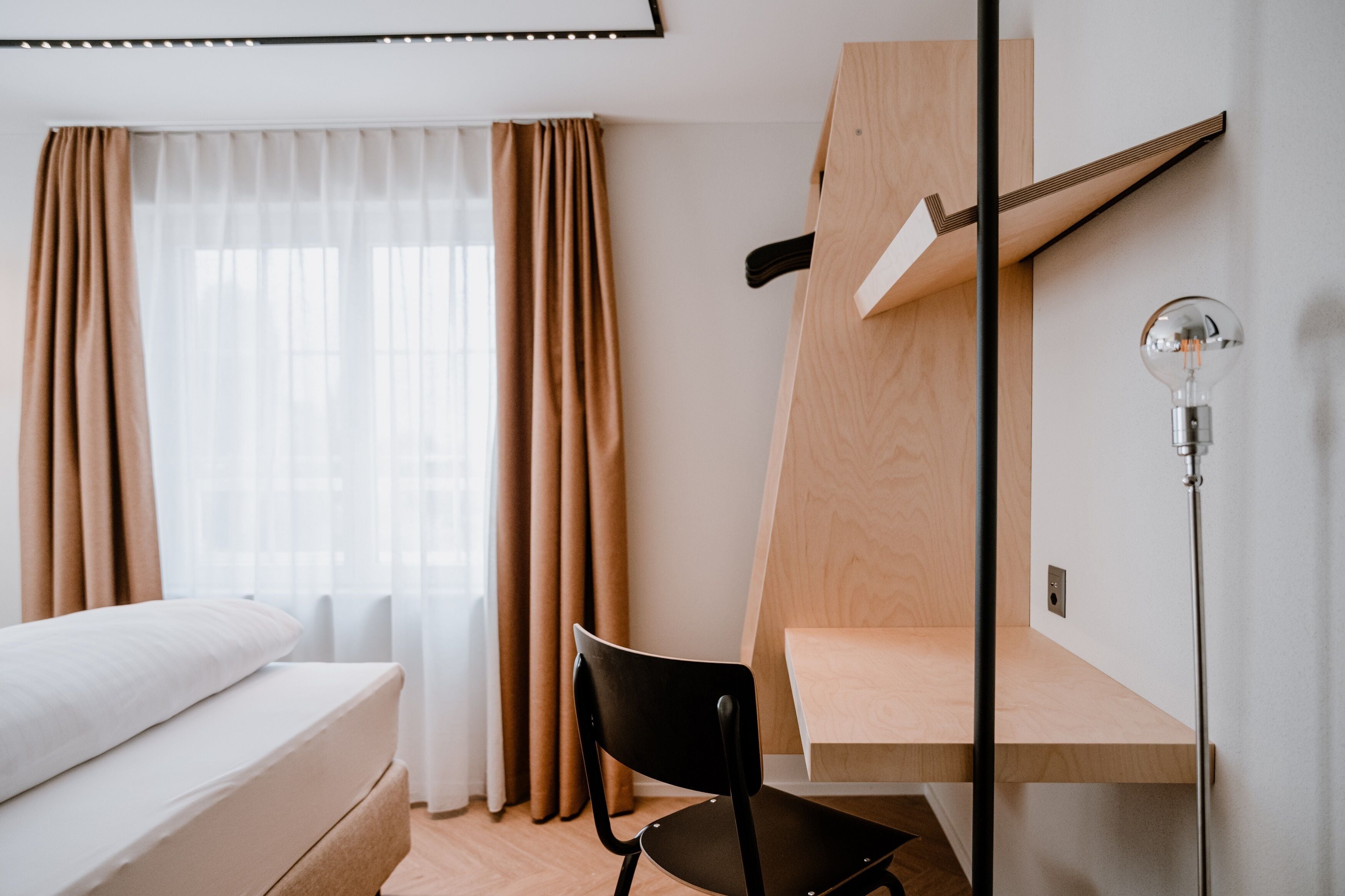 Ein modernes Hotelzimmer mit einem Bett, einem Schreibtisch und einer Lampe.