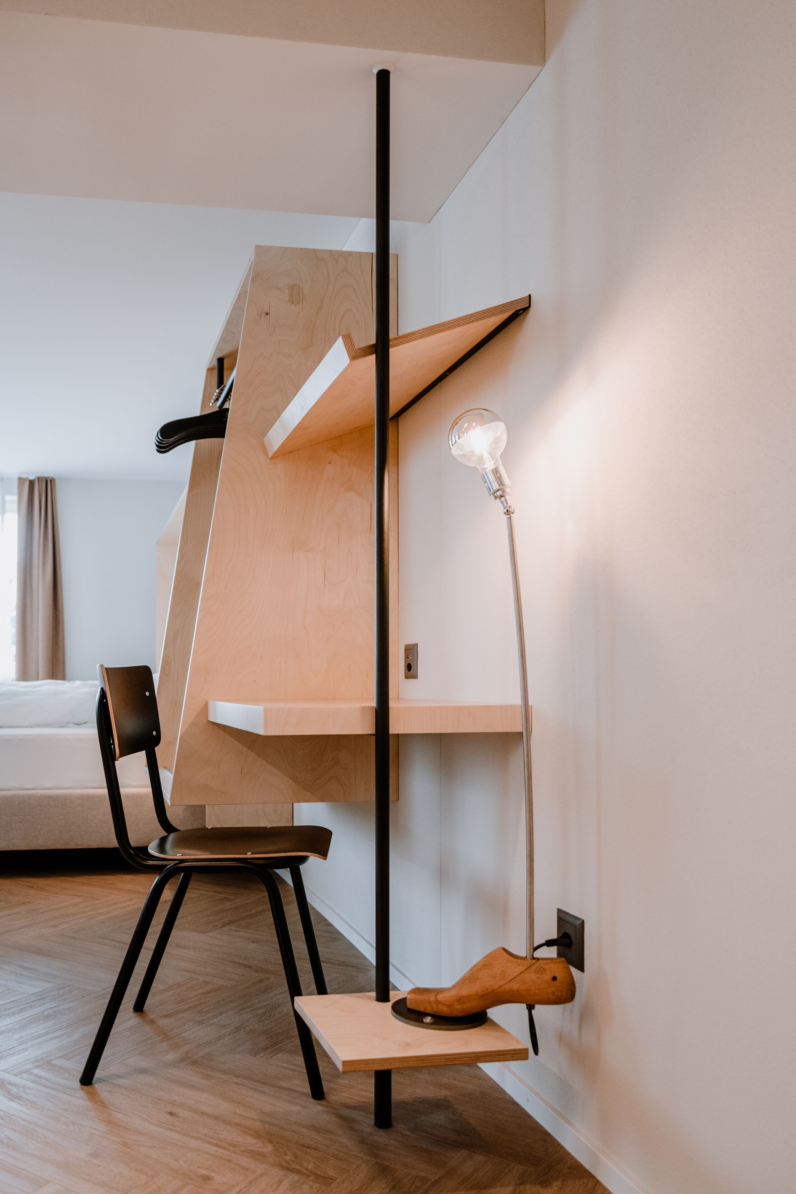 Een moderne kamer met een houten stapelbed, een bureau met stoel, en een vloerlamp.