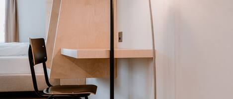 Una habitación moderna con una cama litera de madera, un escritorio con una silla y una lámpara de pie.