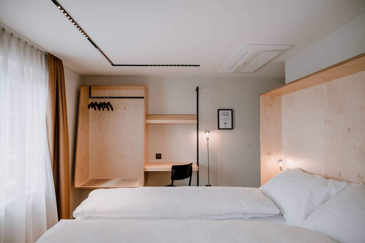 A hotel room with a bed, a desk, a chair, and a wardrobe.