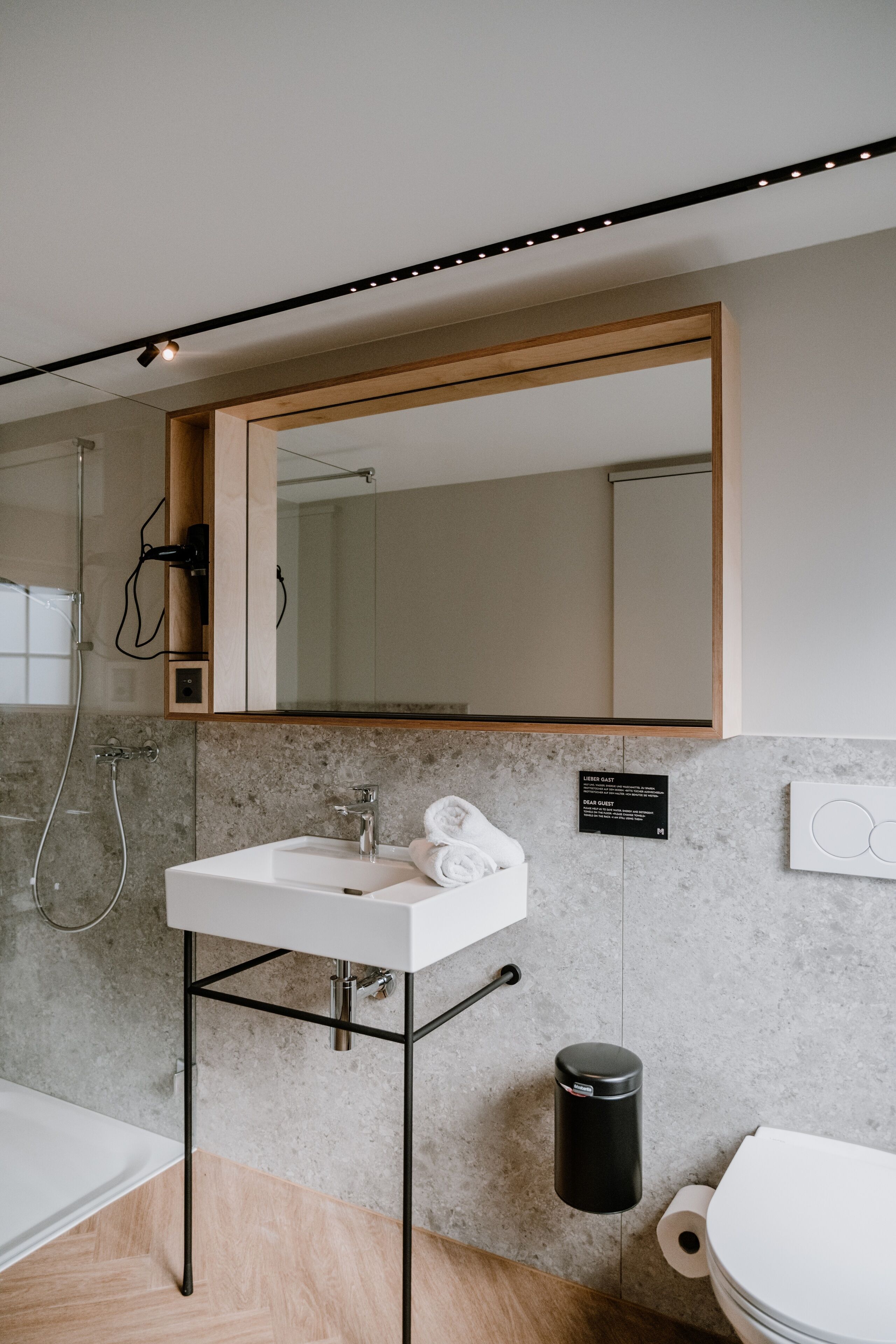 A modern bathroom with a white sink, mirror, and toilet.