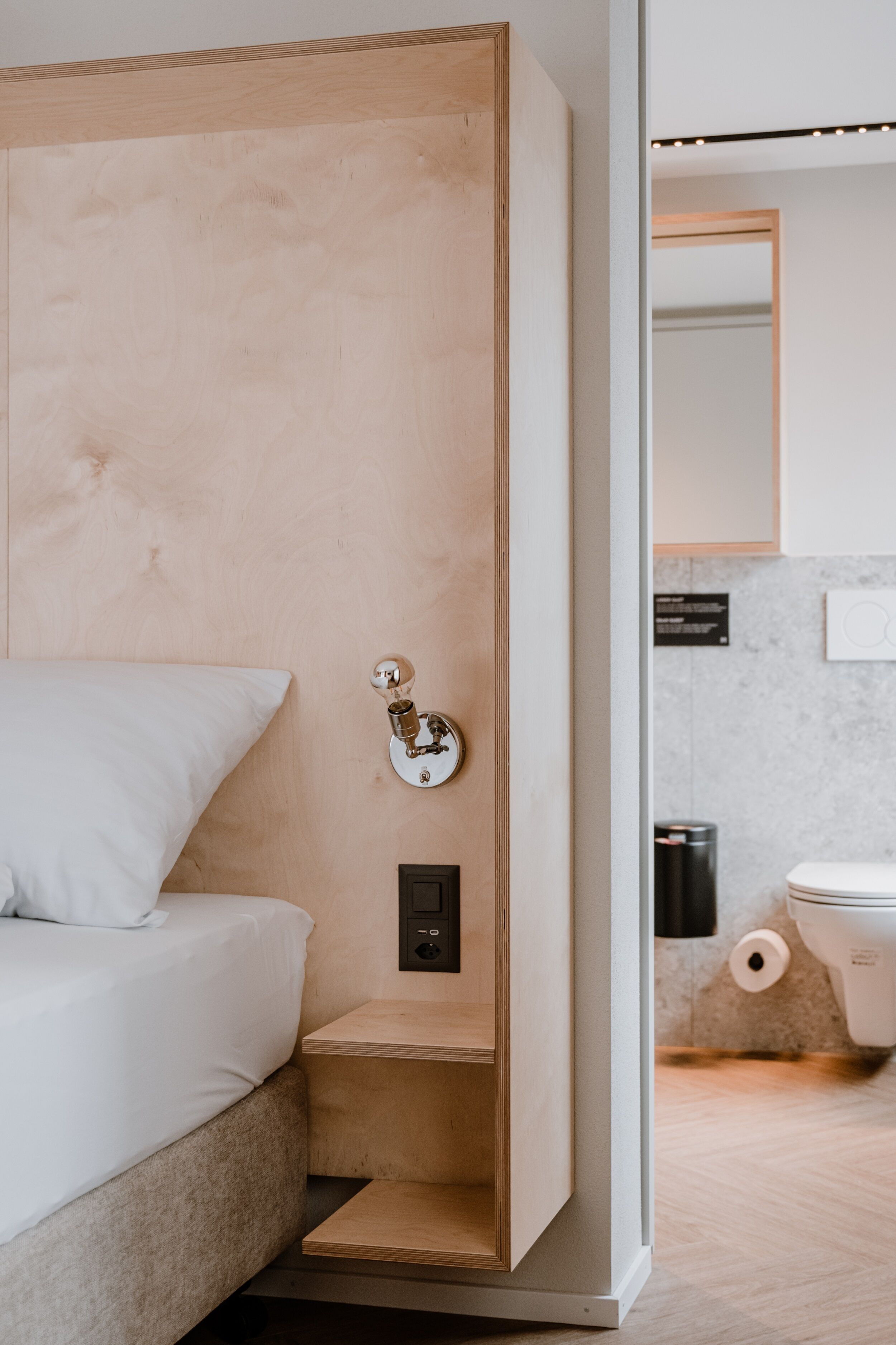 A modern bathroom with a wooden vanity, a toilet, and a mirror.