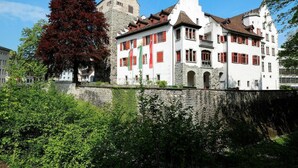 Un edificio storico con un muro in pietra e un grande albero di fronte.