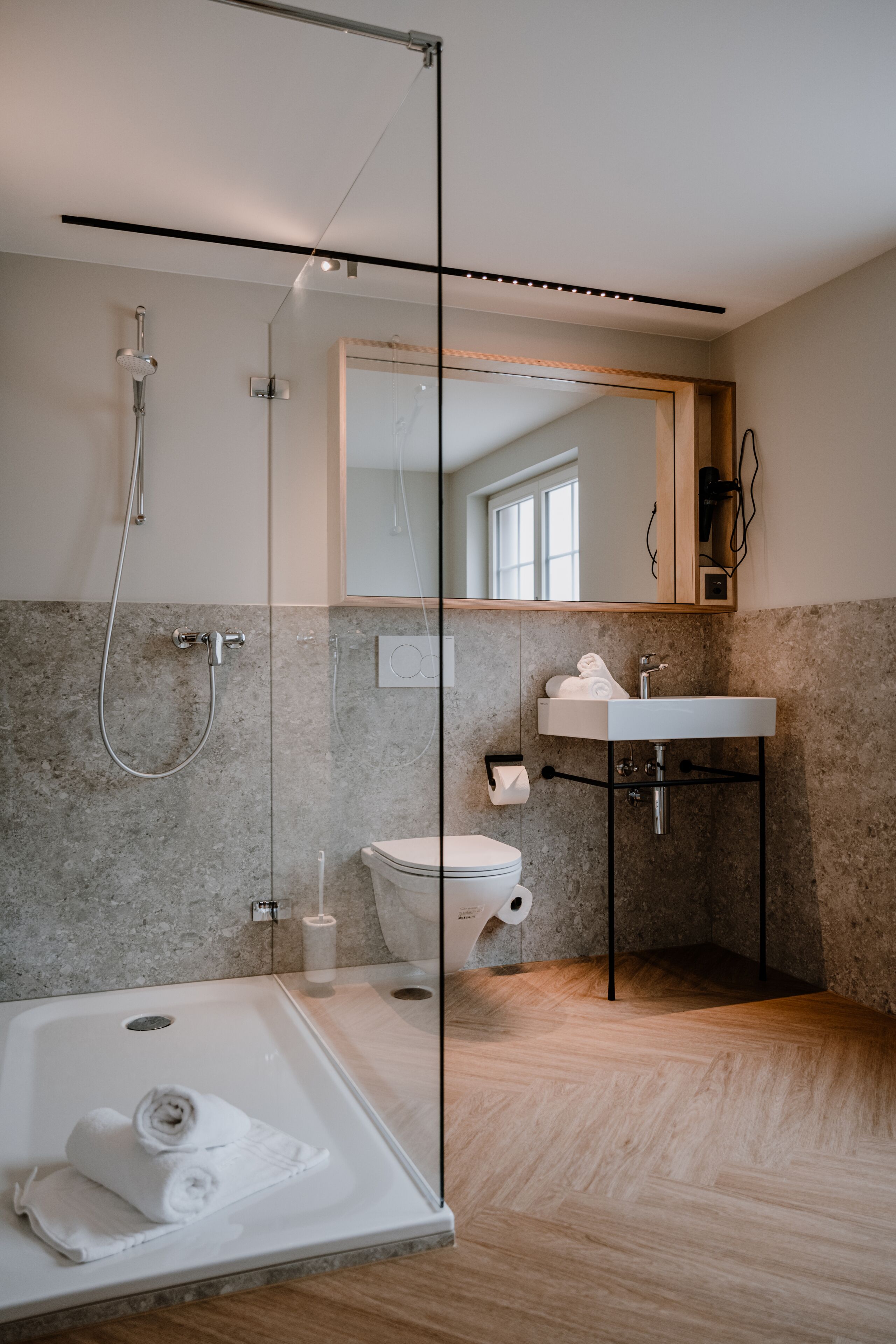 A modern bathroom with a glass-enclosed shower, a white sink, and a toilet.