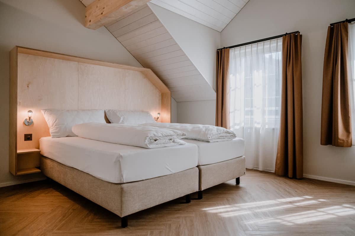 A modern bedroom with a wooden headboard, a double bed, and a skylight.