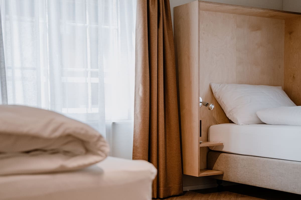 A hotel room with a bed, a sofa, and a window with curtains.