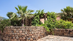 Un muro de piedra con un sendero de piedra que conduce a un edificio con una pérgola de madera.