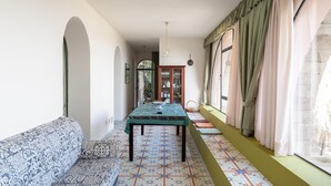 Un couloir avec un sol à motifs, un canapé, une table et une fenêtre avec des rideaux.