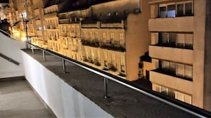 A nighttime view of a row of buildings with balconies and a railing in the foreground.