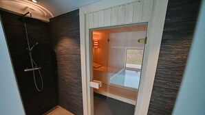 Un baño moderno con sauna de vidrio, zona de ducha y banco de madera.